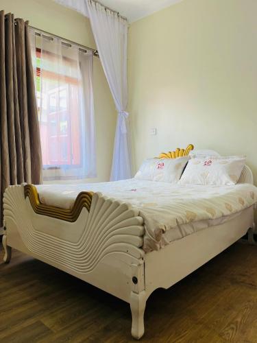 a white bed in a bedroom with a window at St. Patrick’s Forest House in Entebbe