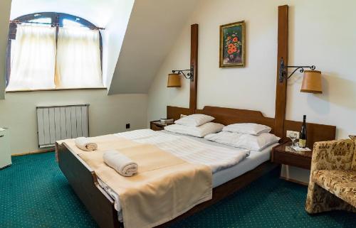 een slaapkamer met een groot bed en een stoel bij Gasthof Laci Betyár in Hajdúszoboszló