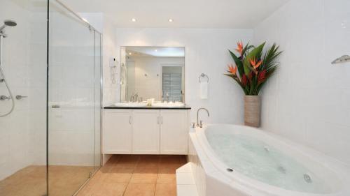 a bathroom with a tub and a sink and a shower at Cayman Villas Port Douglas in Port Douglas