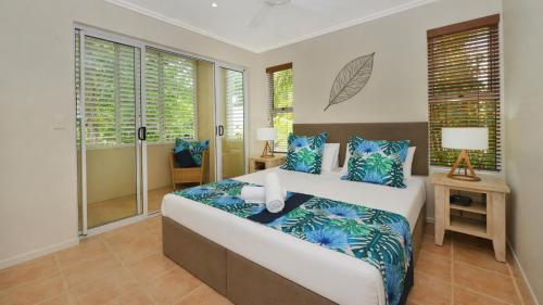 a bedroom with a large bed with blue pillows at Cayman Villas Port Douglas in Port Douglas
