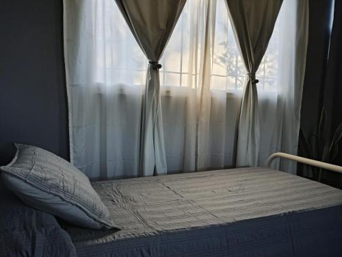 a bed in front of a window with curtains at Alojamiento RuOli in Valle Hermoso