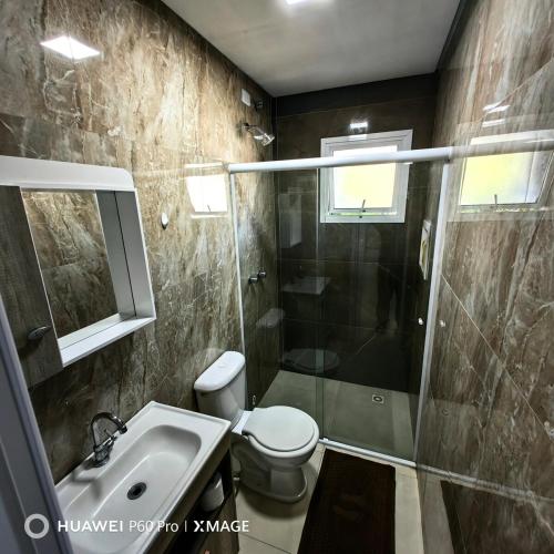 a bathroom with a shower and a toilet and a sink at Apt 08, aconchegante e prático, para sua estadia in Igrejinha