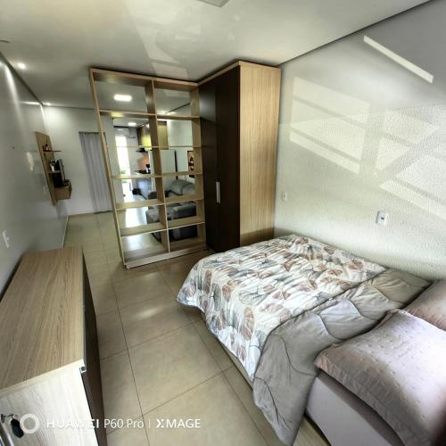 a bedroom with a bed and a mirror at Apt 08, aconchegante e prático, para sua estadia in Igrejinha