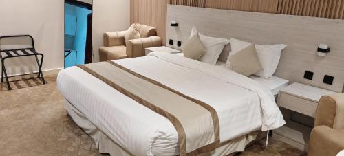 a bedroom with a large white bed and a chair at السناء للشقق المخدومة Alsanaa in Jeddah
