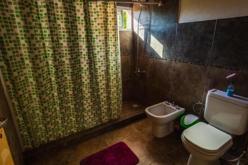 a bathroom with a toilet and a shower curtain at Posada del Guardián in Villa Yacanto