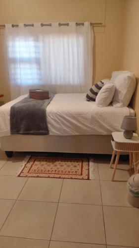 a bedroom with a bed with a window and a rug at Hyponia 1512 in Oshikuku