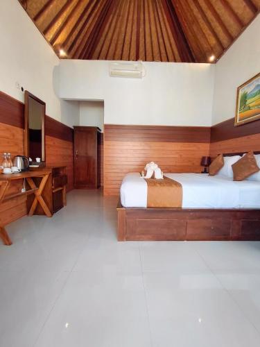 a bedroom with a bed and a desk and a television at Tunjung Kuning Cottage in Nusa Penida