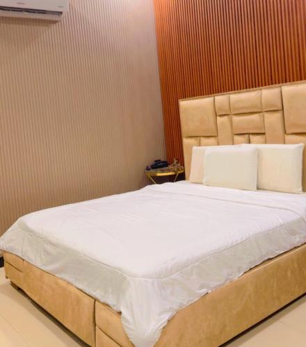 a bedroom with a large bed with white sheets at Sapphire Guest House in Karachi