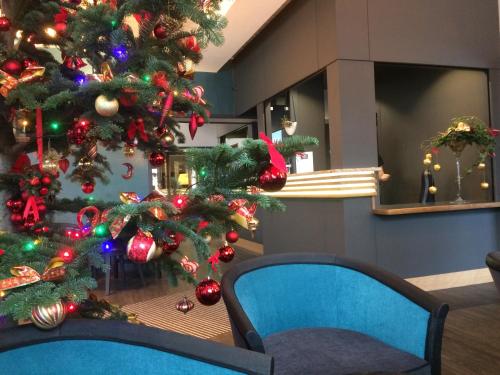 a christmas tree in a room with a blue chair at Hotel de la Jamagne & Spa in Gérardmer