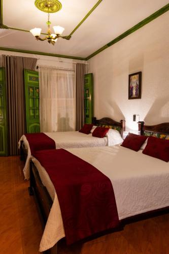 two beds in a bedroom with green and red sheets at HotelSueño Dorado Aguadas in Aguadas