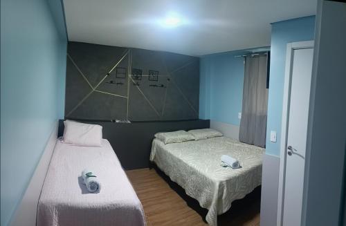 two beds in a small room with blue walls at Pousada Hotel Sol Nascente in Mafra