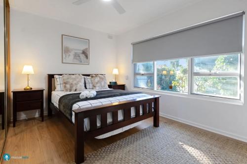 a bedroom with a bed and two windows at Beachside Largs Bay Pet Friendly 3 Bed Haven in Birkenhead
