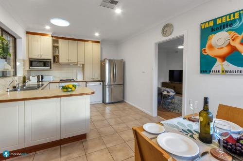 a kitchen with white cabinets and a table with plates on it at Beachside Largs Bay Pet Friendly 3 Bed Haven in Birkenhead