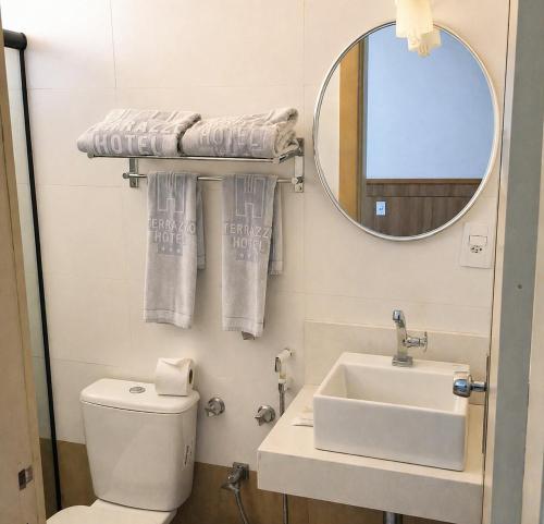 a bathroom with a toilet and a sink and a mirror at Terrazzo Hotel Campos dos Goytacazes in Campos dos Goytacazes