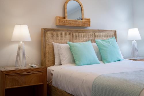 a bedroom with a bed with blue and white pillows at Blue Lagoon Airlie Beach in Airlie Beach