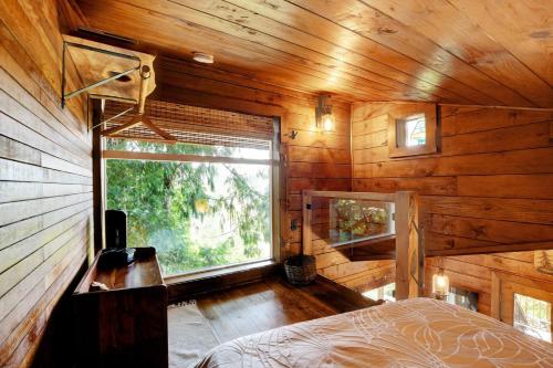 a bedroom with a large window in a wooden cabin at Owl's Perch Treehouse in Sooke