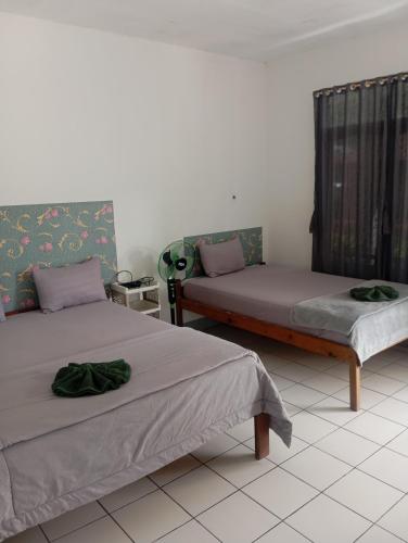 a room with two beds and a window at Hidayah homestay in Kelimutu
