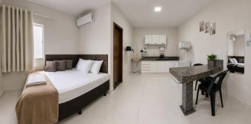 a bedroom with a bed and a desk and a kitchen at AP Completo Próx Centro, Hospitais, Dist Industrial in Montes Claros