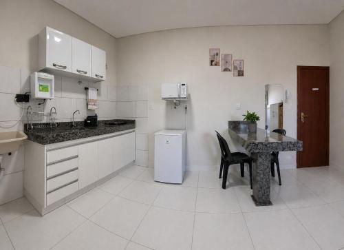 a white kitchen with a table and a refrigerator at AP Completo Próx Centro, Hospitais, Dist Industrial in Montes Claros