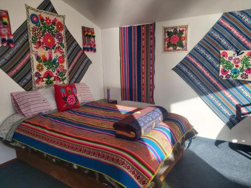 a bedroom with a bed with colorful blankets and pillows at Uros & Titicaca Sunset Comfort Floating cabins in Puno