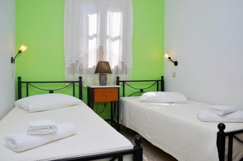 two beds in a room with green walls at Onar Studios in Koufonisia