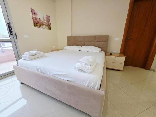 een slaapkamer met een bed met witte lakens en handdoeken bij Thoma's K Studios in Vlorë