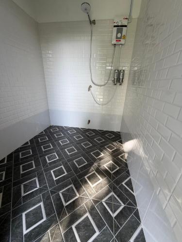a bathroom with a shower and a black and white tile floor at Cosy Garden Khao Sok in Khao Sok National Park