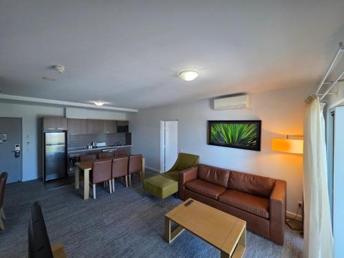 a living room with a couch and a kitchen at Quest Palmerston - Darwin in Palmerston
