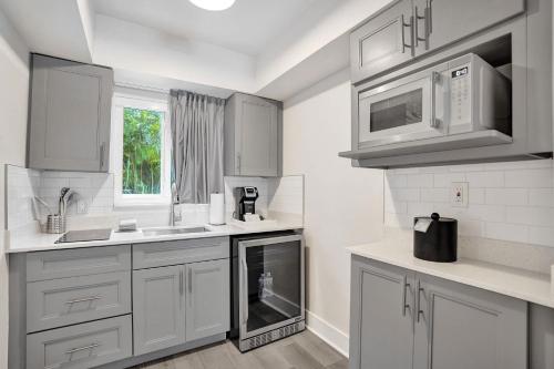 a kitchen with white cabinets and a sink and microwave at Ocean Blvd Two Doubles Suite with Kitchenette in Fort Lauderdale