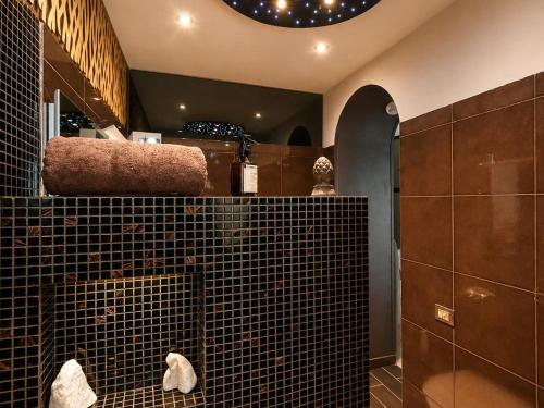 a bathroom with black tiled walls and a mirror at Spacious Apartment near Lake Maggiore in Luino