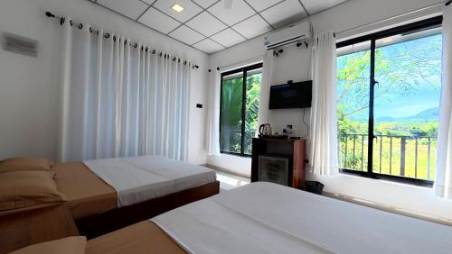 a bedroom with two beds and a tv and windows at Sewana Cottage in Kurunegala