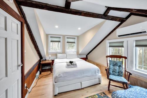 a bedroom with a bed and a chair and windows at 3 Bedroom Cape House by Leavetown Vacations in Sandwich
