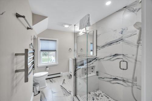 a white bathroom with a shower and a toilet at 3 Bedroom Cape House by Leavetown Vacations in Sandwich