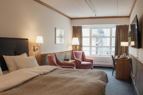 a hotel room with a bed and two chairs at Home Hotel With in Tromsø