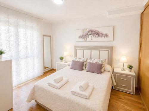 a white bedroom with a large bed with two pillows at APARTAMENTO SOL in Viveiro