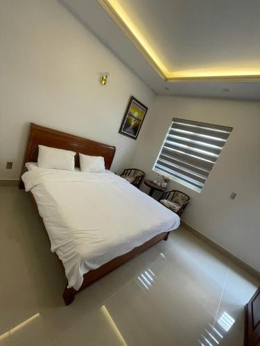 a bedroom with a bed and a window and chairs at Home Me 1 in Dong Hoi