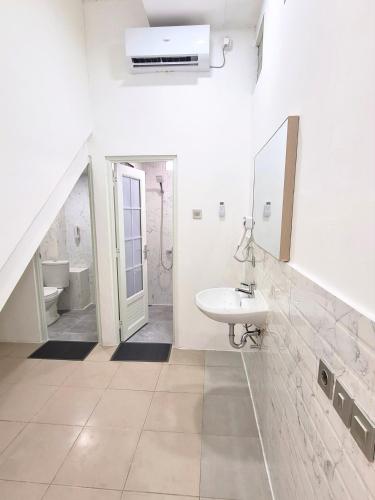 a white bathroom with a sink and a mirror at Bo-Box Guesthouse & Female Only Capsule Lempuyangan - Khusus Wanita in Yogyakarta