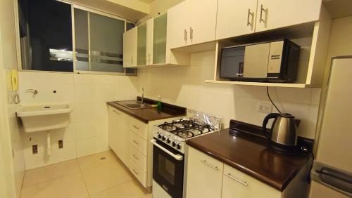 a kitchen with white cabinets and a stove top oven at Departamentos Céntricos en Lima in Lima