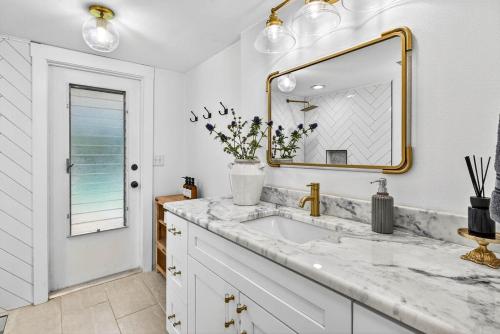 a white bathroom with a sink and a mirror at Spacious Clearwater House 4BR 3BA Private Pool in Clearwater