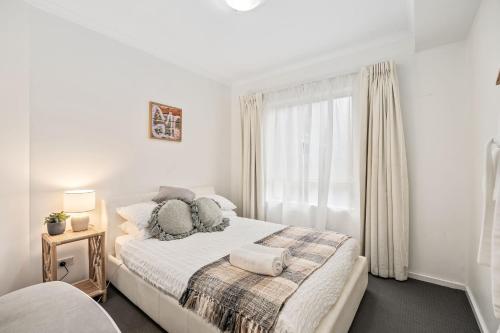 a white bedroom with a bed and a window at Carrington Views - 3 Bedrooms - CBD - Parking in Adelaide