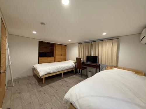 a bedroom with two beds and a desk with a computer at Tiz円居 in Minamiawaji