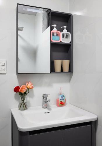 a bathroom sink with a vase of flowers and a mirror at LAN HA PEARL HOTEl in Phù Long