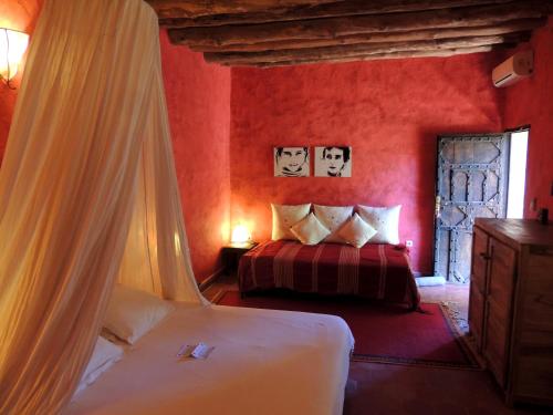 1 dormitorio rojo con 2 camas y ventana en Dar Qamar en Agdz