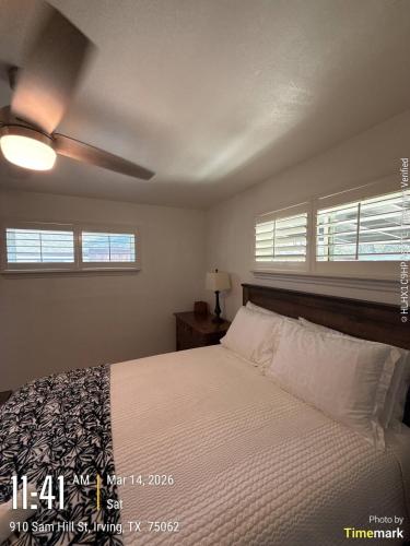 a bedroom with a bed with white sheets and windows at Casa Blanca in Irving