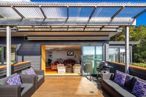 a house with a deck with a pergola at Hekerua Heights with Hot Tub and Seaviews in Oneroa