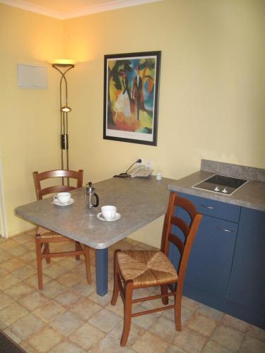 a kitchen with a table with two chairs and a table with at Elliotts Kapiti Coast Motor Lodge in Paraparaumu Beach