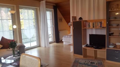 a living room with a television and large windows at Haus Alexandra in Bad Driburg