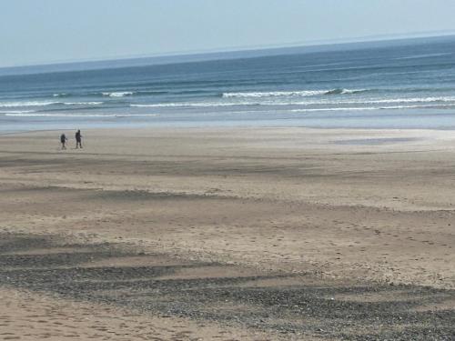 two people walking on a beach near the ocean at La Forgette - Netflix - Cosy in Les Pieux
