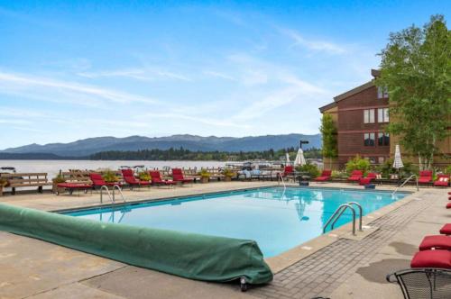 a swimming pool at a resort with chairs and a lake at Lakeside Getaway Beach Access Shared Pool and Grills in McCall