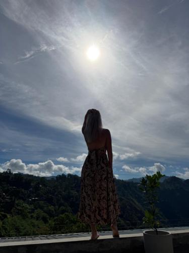 a woman standing on a ledge looking up at the sky at Bethel Ella in Ella